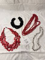 Overview of four necklaces on white surface