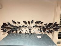 Full frontal view of metal leafy branch wall art on shelf