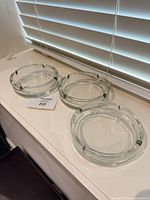 Three clear glass ashtrays on windowsill