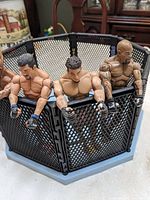 Six UFC action figures seated on edge of octagon cage
