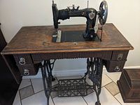 Front view of treadle sewing machine in cabinet showing overall condition