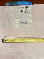 Full view of 10K gold curb chain necklace next to measuring tape showing length