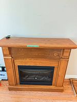 Front view of wood mantel with electric insert and remote on top