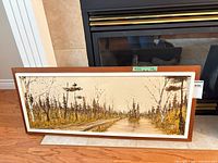 Full view of framed landscape painting against fireplace