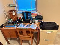 Desk, chair, filing cabinet, lamp, basket, assorted office supplies on desk surface