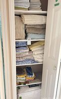 Linen closet shelves with stacked towels and folded sheets