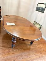 Full view of oval dining table showing turned legs and wood grain