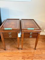 Pair of wood end tables front view showing drawers and legs on casters