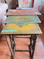 Three nesting tables stacked showing painted tops and turned legs