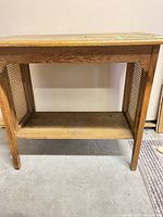 Front view of console table showing cane side panels and lower shelf