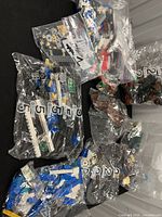 Overview of multiple sealed and opened bags of LEGO pieces in various colours