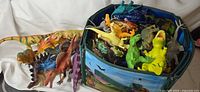 Storage cube filled with assorted dinosaur figures, playmat visible