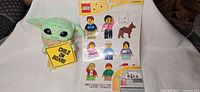 Grogu plush holding Child On Board sign next to LEGO Family sticker sheet