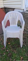 Front view showing stack of five white plastic chairs