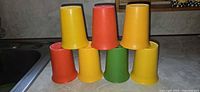 Seven multicolour Tupperware tumblers stacked on countertop