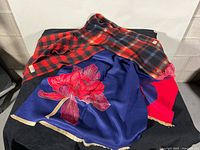 Two scarves displayed: plaid scarf folded over reversible navy floral shawl