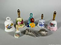 Group shot of six porcelain bells and two cast aluminum seashells