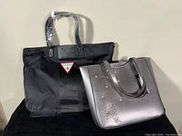 Overall view of Karl Lagerfeld metallic grey tote and Guess black vinyl tote