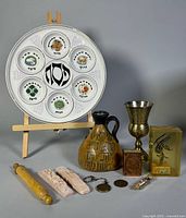 Group shot of all Judaica items including Seder plate, jug, Kiddush cup, mezuzah cases, coins, acrylic menorah block, rolling pin and holders