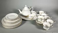 Complete set laid out: teapot, creamer, sugar bowl on platter, stacks of plates, six teacups