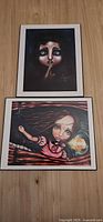 Both matted Angelina Wrona prints on wood surface