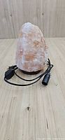 Front view of Himalayan salt lamp on wood base with cord and socket