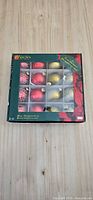 Front of boxed ornament set showing 16 red and gold glass balls