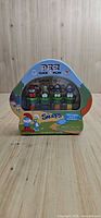 Front of mushroom-shaped tin showing four Smurfs PEZ dispensers inside packaging