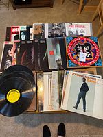 Tabletop view of stacked vinyl records showing covers including The Beatles, KISS, Johnny Mathis
