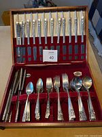 Open wooden chest showing complete assortment of silver flatware and red velvet interior