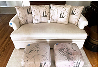 Full view of cream sofa with matching ottomans and cushions