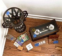 Group shot showing steel vase, crystal vase, balance scale, coins, books, weights