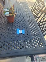 close view of latticed metal patio table with chairs visible