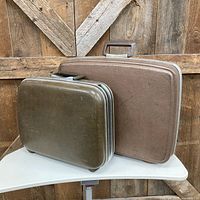 Two vintage suitcases side by side showing colors, handles and trim