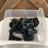Top view of plastic drawer showing numerous power adapters with cords