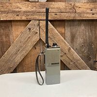 Front view of handheld radio showing speaker grille, model label and antenna