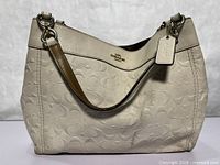 Front view of Coach cream embossed leather hobo bag