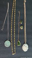 All five jewellery pieces laid out vertically on dark fabric