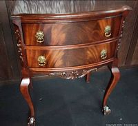 Front angled view showing drawers, brass pulls, carving, cabriole legs and claw feet