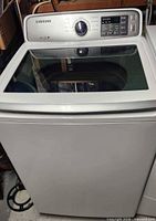 Full front view of Samsung top-load washer showing glass lid and white exterior