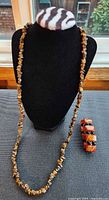 Full view of tiger's eye chip necklace draped on display and agate/onyx bracelet beside it