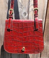 Front view of burgundy croc-embossed leather bag hanging, showing overall condition and texture