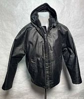 Front view of black waxed denim hooded jacket on stand