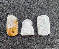 Front view of three carved jade pendants