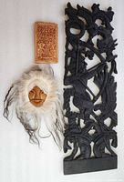 All three items: fur-trimmed mask, black carved warrior panel, small relief plaque