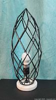 front view of metal cage lamp showing bulb and stone base