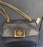 Front view of Coach Cassidy purse showing black leather, gold turnlock and chain strap