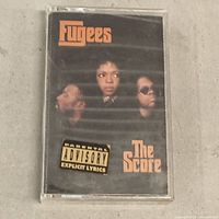 Front of cassette case showing Fugees The Score cover art and explicit lyrics label