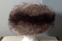 Side view of brown fur hat on stand