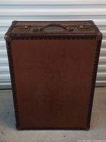 Front view of brown metal trunk showing riveted edges and wear